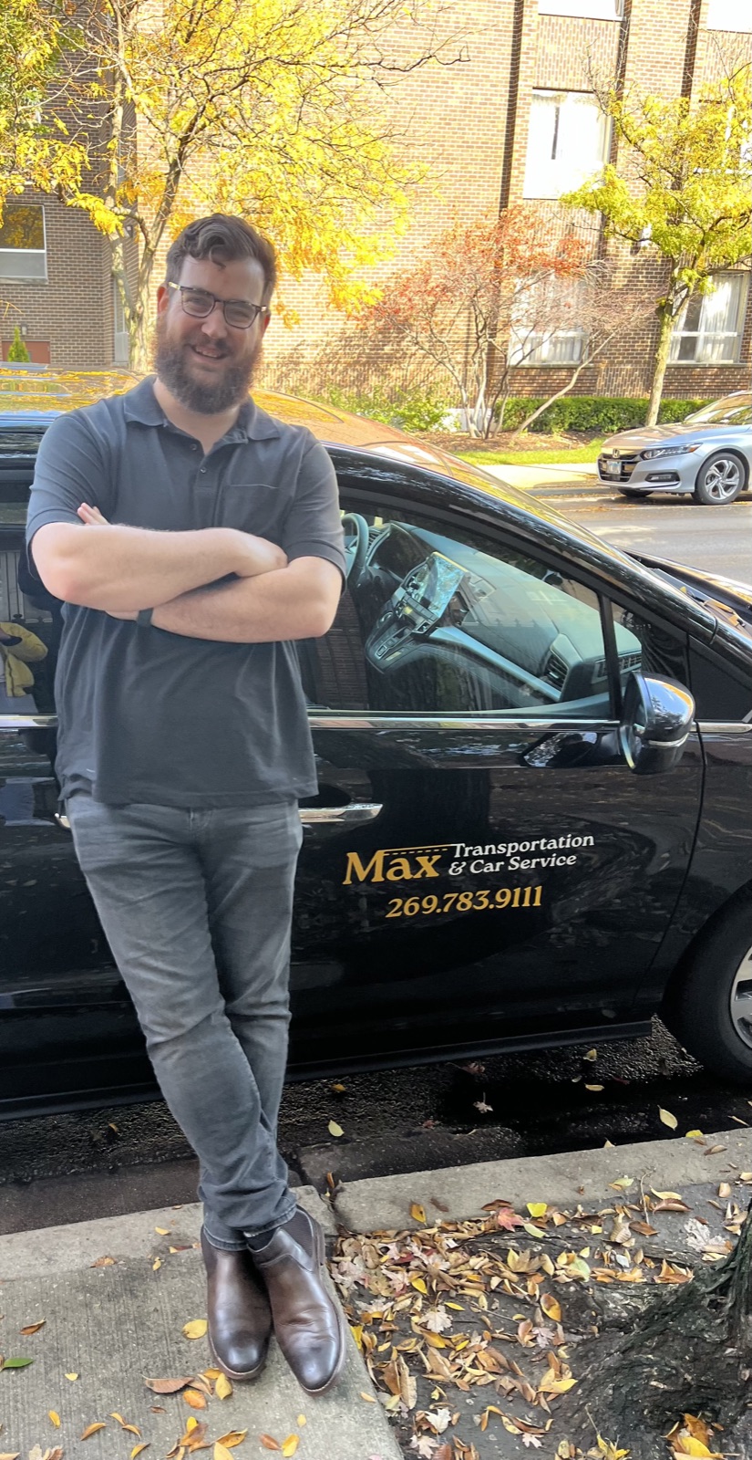 Max, owner of Max Transportation & Car Service, standing beside his black sedan with gold door lettering